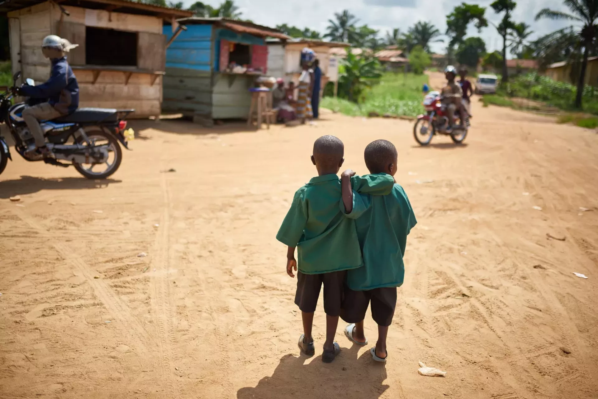 School boys walk arm-in-arm down a road in Kenema, Kenema District, Sierra Leone
